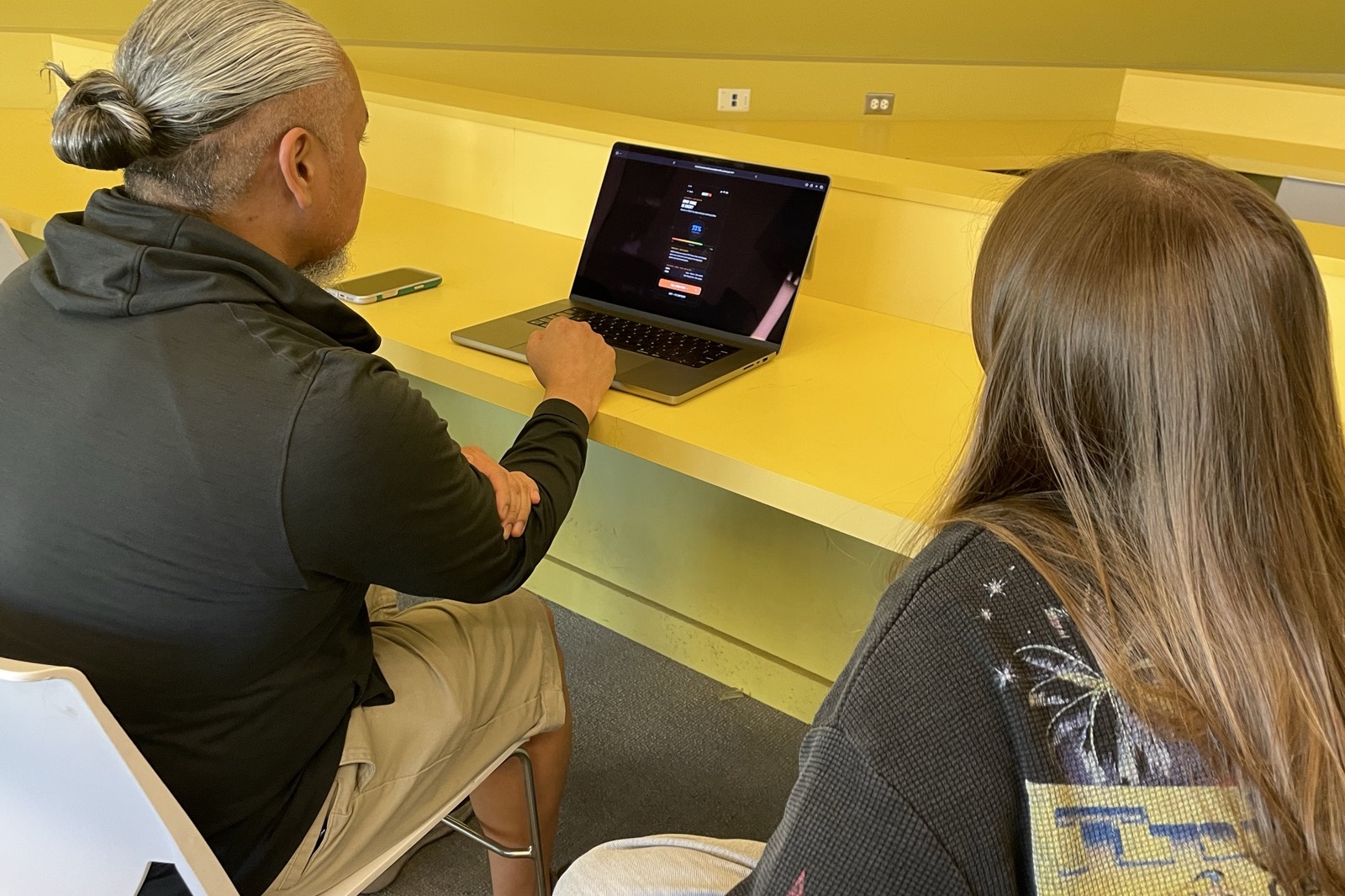 A participant using the NextFix prototype on a laptop while a teammate observes
